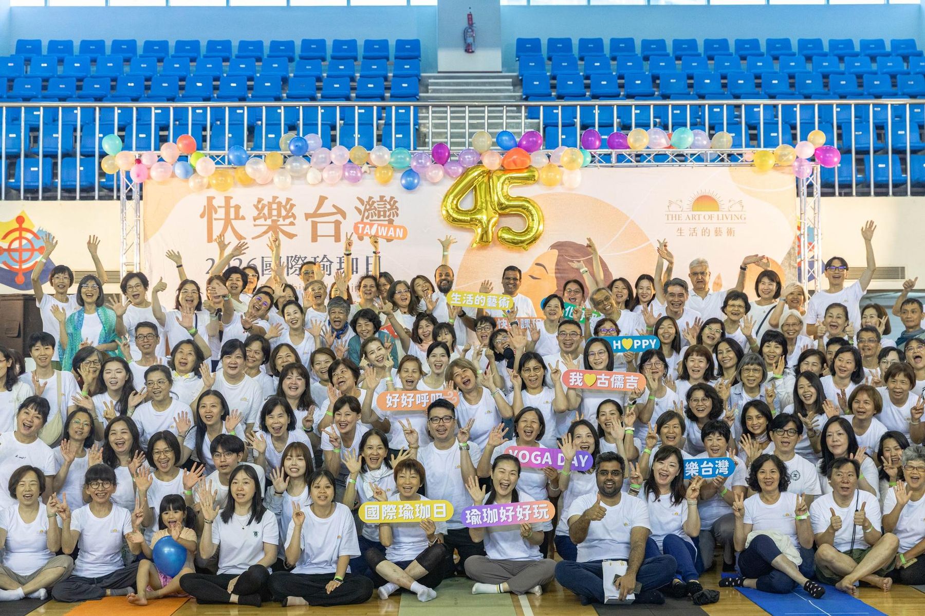 2026 國際瑜珈日臺北場，上百位台灣學員在「快樂台灣」背板前的大合照